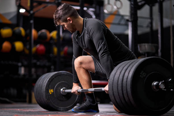 istock Athlete standing on his knee preparing to make deadlift at gym 1472539754