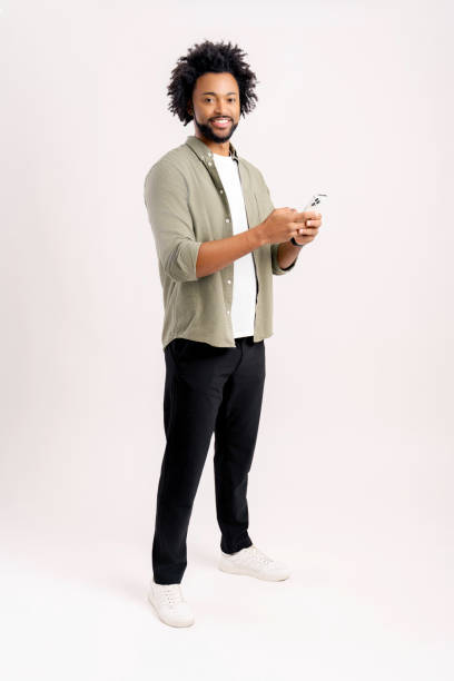 istock Happy handsome young man is using smartphone and texting, messaging in social networks, positive guy using mobile app, studio shot isolated on white 1472540054