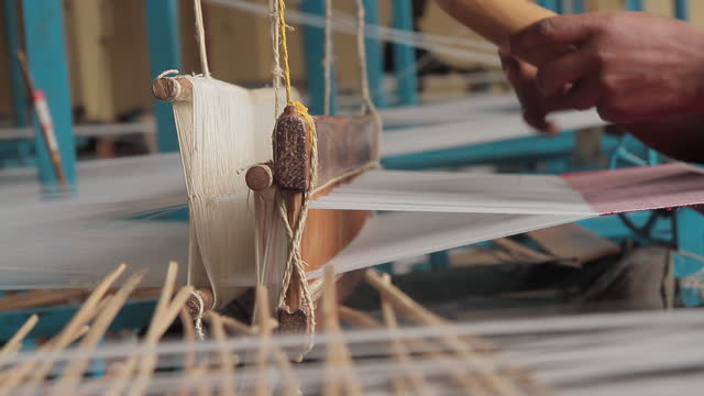 Weaving cotton in a developing country. Traditional loom. Working fast