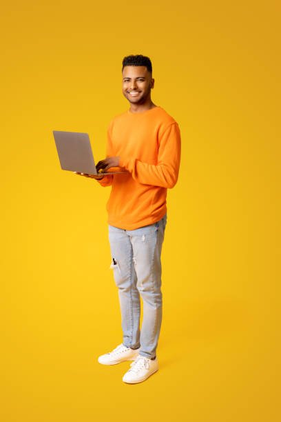 istock Smiling handsome Indian young 20s man using laptop computer for web surfing or studying on the distance 1472547029