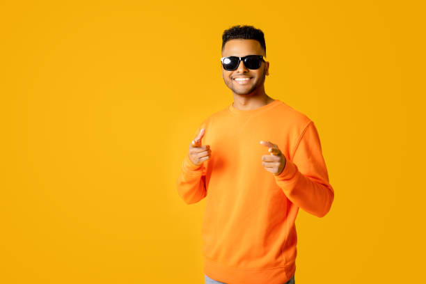 istock Stylish handsome Indian young man wearing casual orange pullover and sunglasses has good mood 1472547555