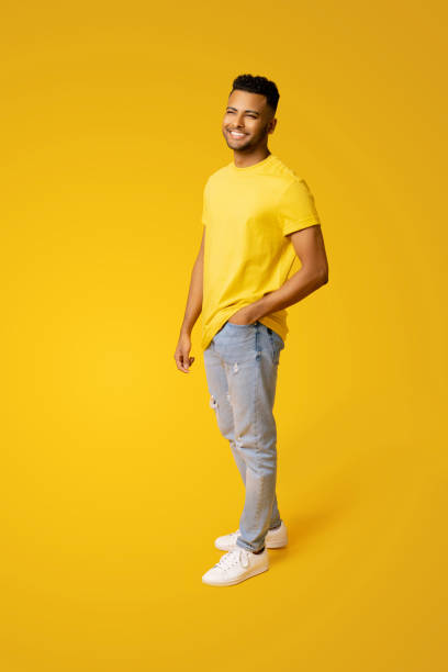 Pleased indian man in casual wear stands isolated on yellow, male student, young handsome guy standing stock photo