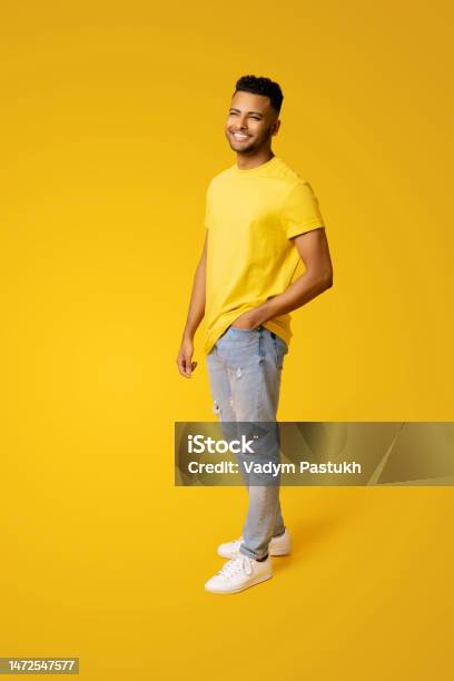 Pleased Indian Man In Casual Wear Stands Isolated On Yellow Male Student Young Handsome Guy Standing Stock Photo - Download Image Now