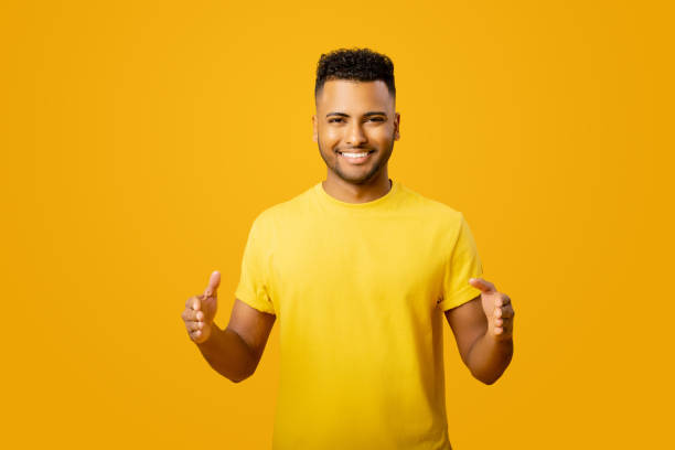 istock Young handsome Arab man measuring empty space, showing size standing isolated on yellow, cheerful indian man holding hands in front of him, sizing 1472547601