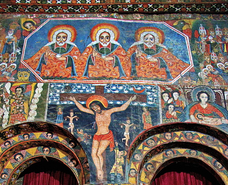 In Debre Berhan Selassie Church, painting of the Holy Trinity (all  three persons are  painted to look the same) is over the doors leading to the Holy of Holies.  \nDebre Berhan Selassie Church is located in northern Ethiopia in the town of Gondar.\nBuilding  and paintings date back to the 18th century. Artist is unknown,  although local tradition attributes most paintings to the 17th-century artist Haile Meskel.