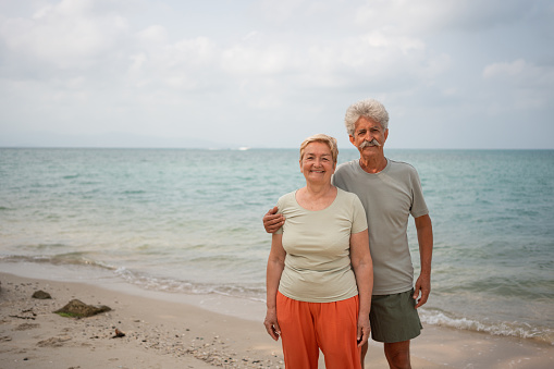 Portrait of active senior couple smiling towards the camera after workout on the becah.