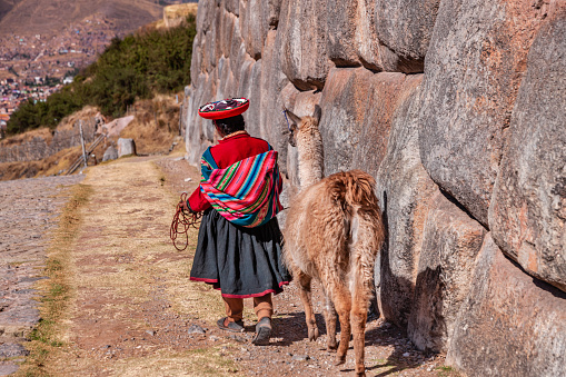 Peruvian girl wearing national clothing walking with llama near Cuzco. The Sacred Valley of the Incas or Urubamba Valley is a valley in the Andes  of Peru, close to the Inca capital of Cusco and below the ancient sacred city of Machu Picchu. The valley is generally understood to include everything between Pisac  and Ollantaytambo, parallel to the Urubamba River, or Vilcanota River or Wilcamayu, as this Sacred river is called when passing through the valley. It is fed by numerous rivers which descend through adjoining valleys and gorges, and contains numerous archaeological remains and villages. The valley was appreciated by the Incas due to its special geographical and climatic qualities. It was one of the empire's main points for the extraction of natural wealth, and the best place for maize production in Peru.
