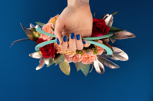 Beautiful woman hands with manicure holding roses against classic blue background