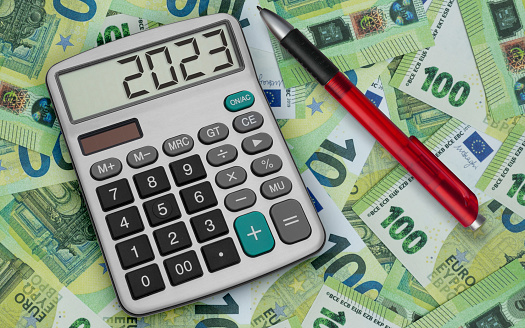Desktop calculator with euro banknotes and a red pen in the background