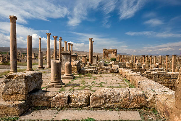 Forum of ancient Thamugadi Algeria. Timgad (ancient Thamugadi or Thamugas). Row of Corinthian columns at the forum and colonnade along Decumanus Maximus street (on right) terminated Trajan's Arch. Please see my other images of Roman places in Tunisia and Libya algeria stock pictures, royalty-free photos & images