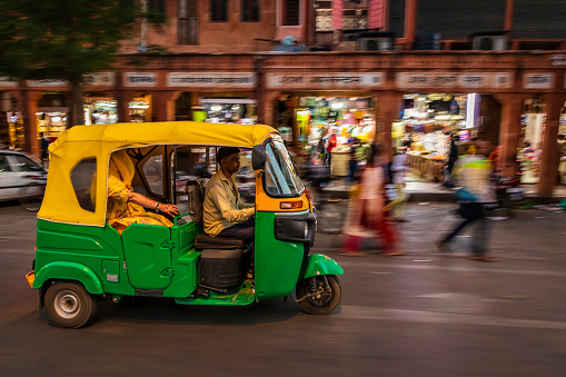 Indian man drives auto rickshaw (tuk-tuk) on streets of Rajasthan, India.