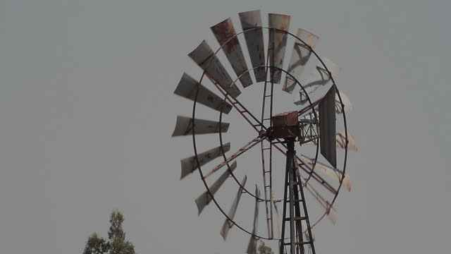 Old-fashioned windmill with a tail fin spinning on strong wind