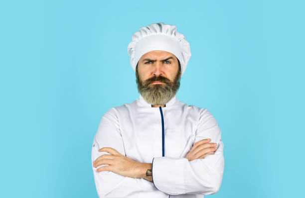 Two male smiling chefs in kitchen and one chef making hand gesture