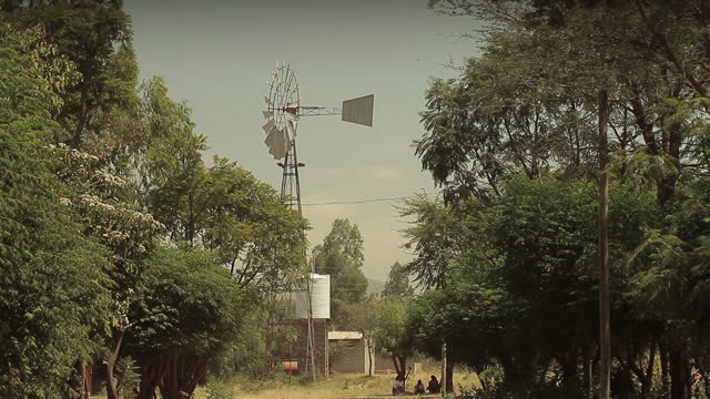 Old-fashioned windmill with a tail fin spinning on wind in a rural area