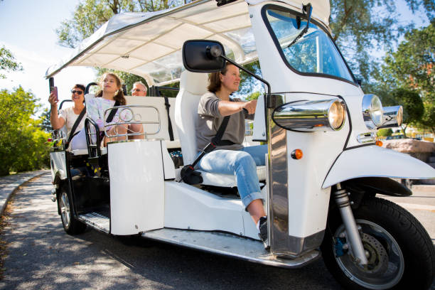 A group of tourists driving through the city center in tuk-tuk electric car stock photo