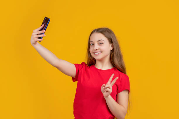 istock happy kid with smartphone on yellow background. peace 1472561729