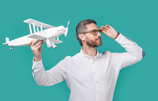photo of man launch aspirations with toy plane, motivation. man launch aspirations isolated on blue background. man launch aspirations in studio. man launch aspirations with plane.
