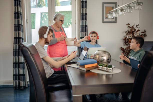 wielopokoleniowa rodzina wykorzystująca technologię bezprzewodową w domu - grandparent using computer laptop dining table zdjęcia i obrazy z banku zdjęć