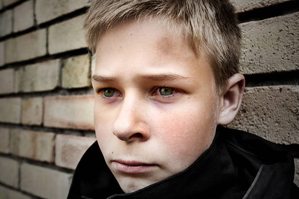 istock Boy with bruised head leaning against brick wall 147257909