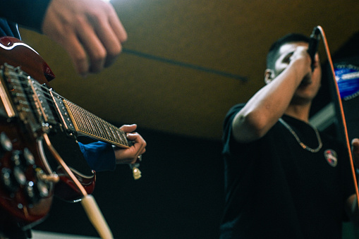 A guitarist and a main vocalist rehearsing in a music studio
