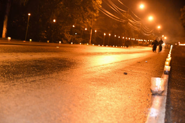 Dark and desolate street on a holy week day, with a candlelight walker and the shadow of two monks.