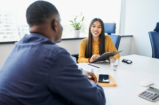 Young woman recruiting startup employee talking with man during job interview in the office
