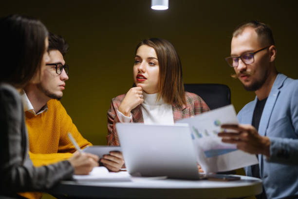 istock Workaholics businesspeople brainstorming financial company ideas analyzing strategy paperwork late at night in business office. 1472582731