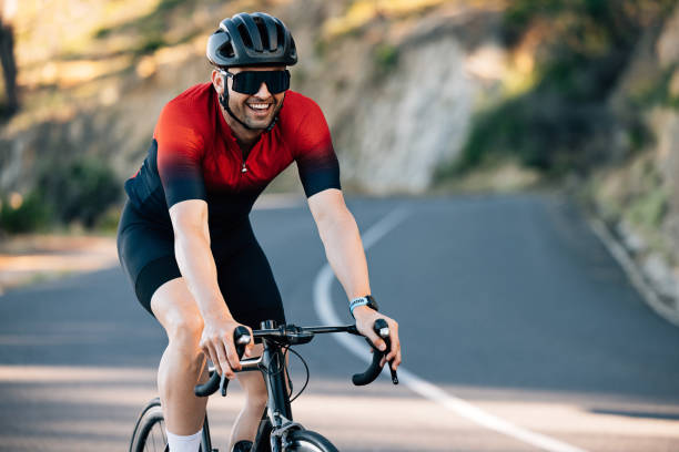 Young male cyclist smiling while riding a road bike on a hill stock photo