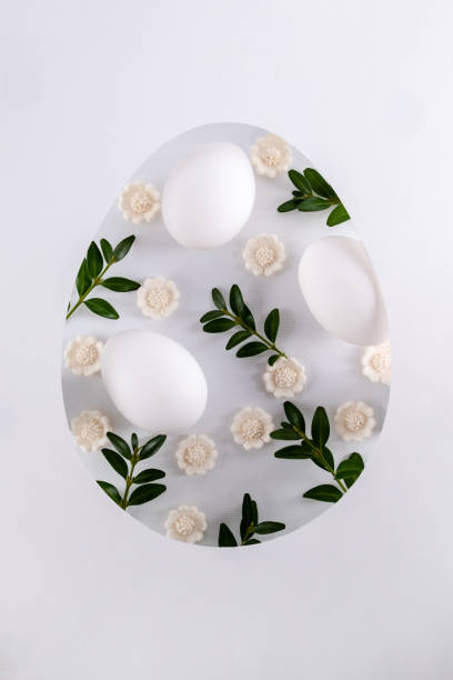 istock Easter card with paper cut egg shape frame with Easter egg spring flowers and green leaves. Flat lay, top view 1472585865