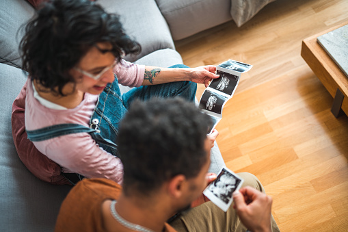 High angle view of an African American And Hispanic couple looking at ultrasound images of their baby. They are excited to be parents for the first time.