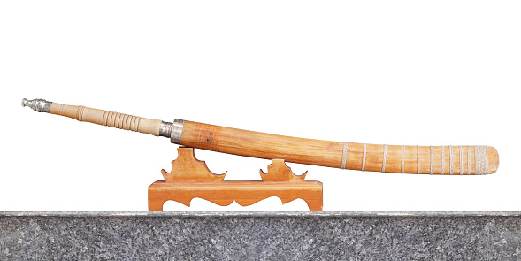 side view steel and wooden sword is in the scabbard, on a wooden stand, on the tiled floor, white background, object, vintage, gift, decor, fashion, copy space