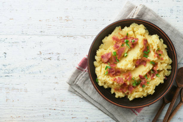 istock Mashed potatoes. Bacon mashed potatoes with green onion, pepper and cheddar cheese in bowl on old wooden backgrounds. Delicious creamy mashed potatoes. Top view. 1472594799