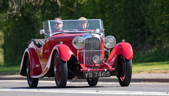 Bicester,UK 24th Apr 2022. Sunday 24th April 2022 was Drive It Day when Owners of classic and vintage cars drive their cars to raise money for Childline. It celebrates the occasion in 1900 when 65 vehicles drove from London to Edinburgh returning to London to prove the viability of the motor car. Pictured is a red  1936 Lagonda Rapier Ranalah tourer driving on an English country road