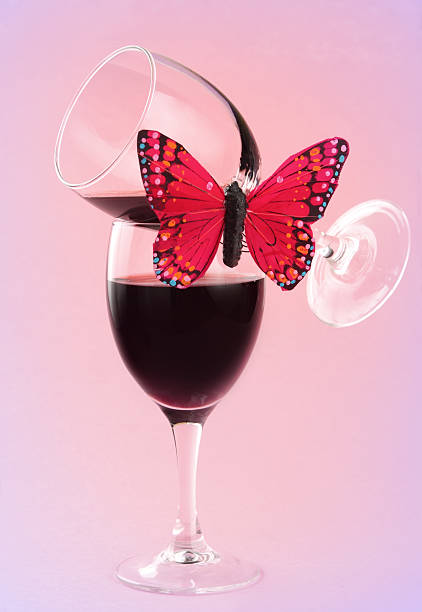 two stacked glass of red wine with a fake butterfly