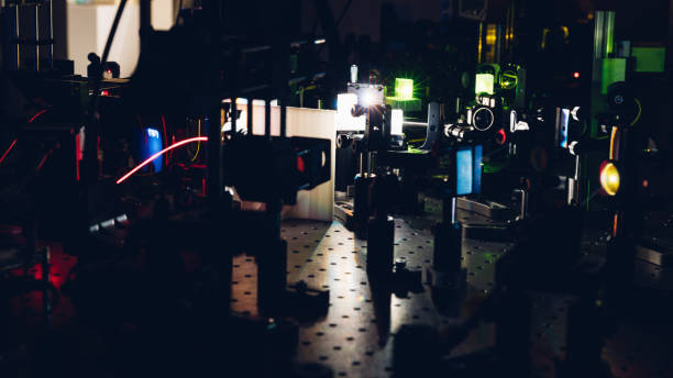 istock Experiment with laser device in optical laboratory. Experiment in optic lab with laser device. Experiment in optic lab with laser device. 1472599734