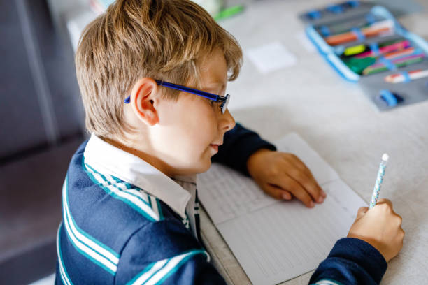istock Hard-working happy school kid boy making homework during quarantine time from corona pandemic disease. Healthy child writing with pen, staying at home. Homeschooling concept 1472601227