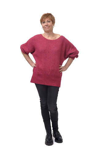 full length portrait of standing woman in tight jean pants and sweater looking at camera with hands akimbo on white background