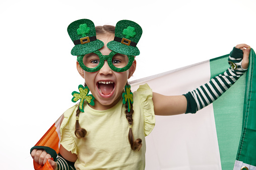 Young girl in leprechaun costume against white background.