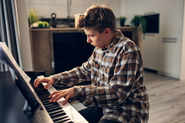 istock Teenage boy practicing piano at home 1472613008