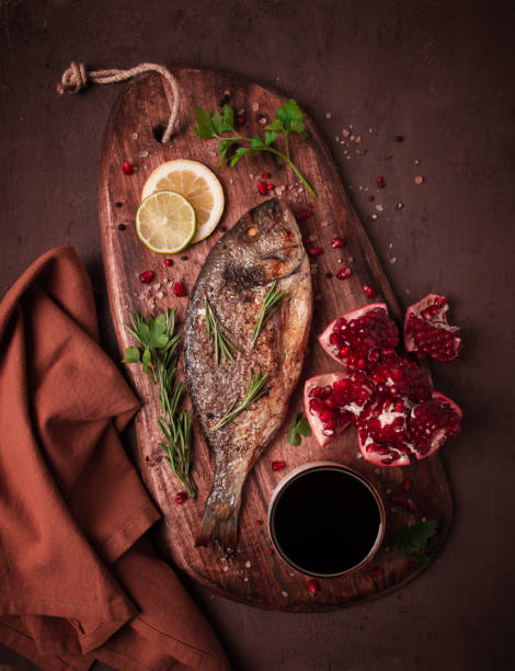Fried dorado fish, with spices and herbs, on a wooden board, pomegranate sauce, close-up, no people,