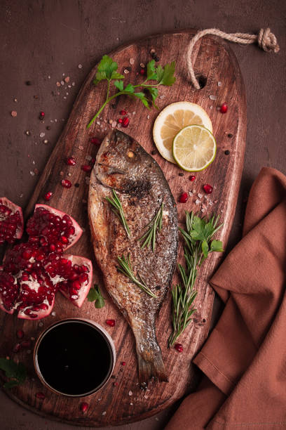 Fried dorado fish, with spices and herbs, on a wooden board, pomegranate sauce, close-up, no people,