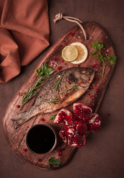 Fried dorado fish, with spices and herbs, on a wooden board, pomegranate sauce, close-up, no people,