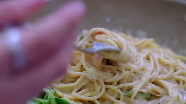 close up eating spaghetti carbonara with fork with cream and vegetables