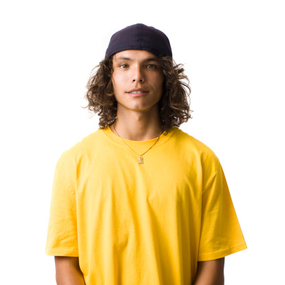 A teen with a baseball cap in a studio smiles