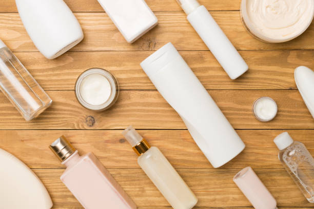 istock Different cosmetic bottles and container on wooden background, top view 1472617280