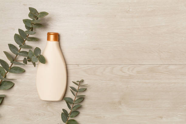 istock Cosmetic bottle with eucalyptus branch on wooden background, top view 1472617285