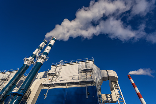 External view of the modern biomass power plant with smoking chimneys on the beautiful blue sky background
