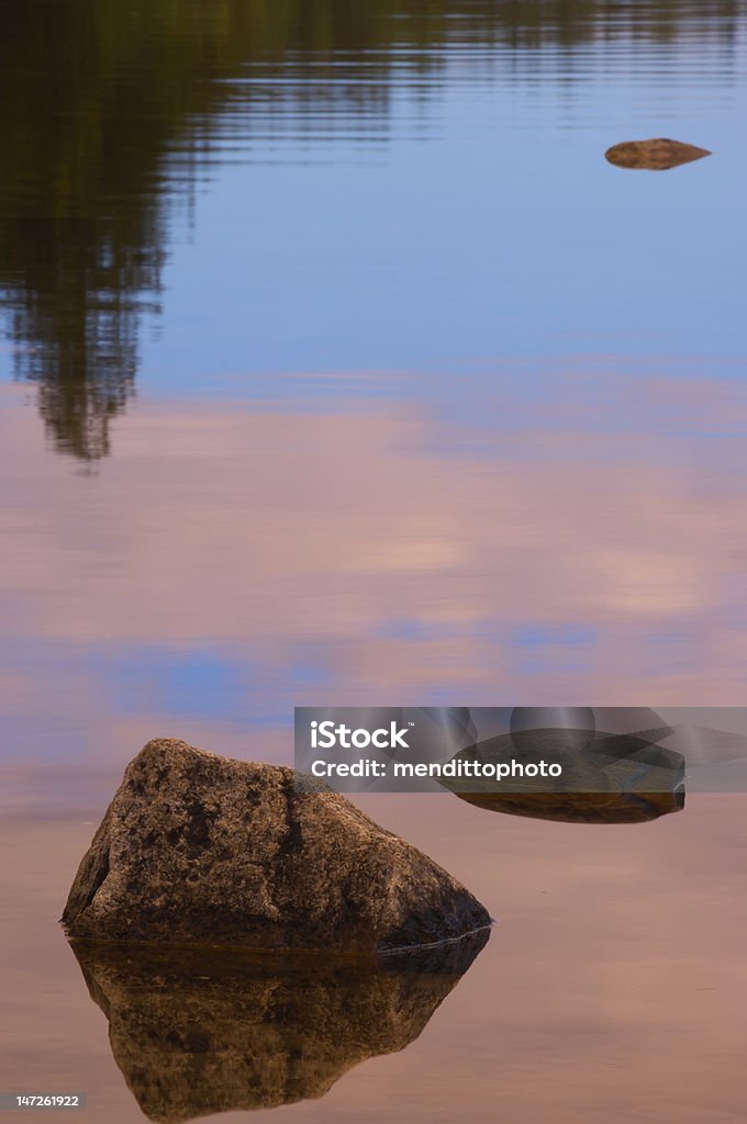 Three morning rocks on Jordan Pond Jordan Pond, Acadia National Park, Bar Harbor, ME (US). Reflection of trees in background. Blue Stock Photo