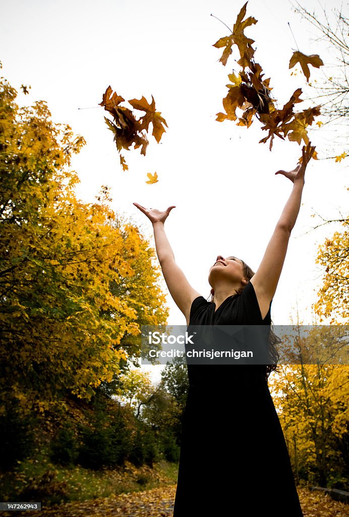 Girl throwing leaves into the air Young female adult tossing fall leaves into the air Achievement Stock Photo