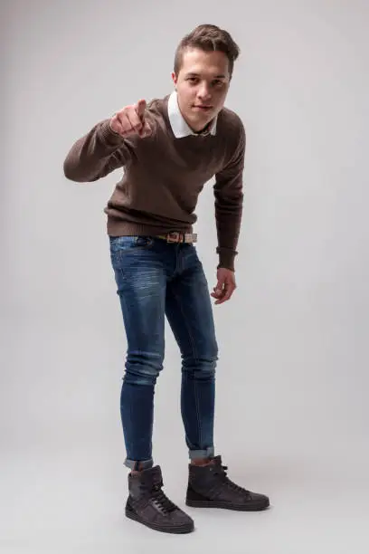 Photo of Young man in topknot, ankle-high skinny jeans, pointing